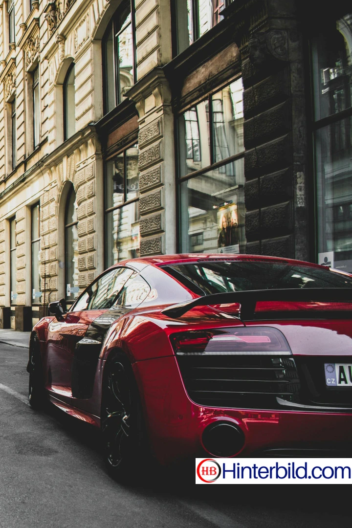 Rotes und schwarzes Audi R8 Coupé vor Betongebäude